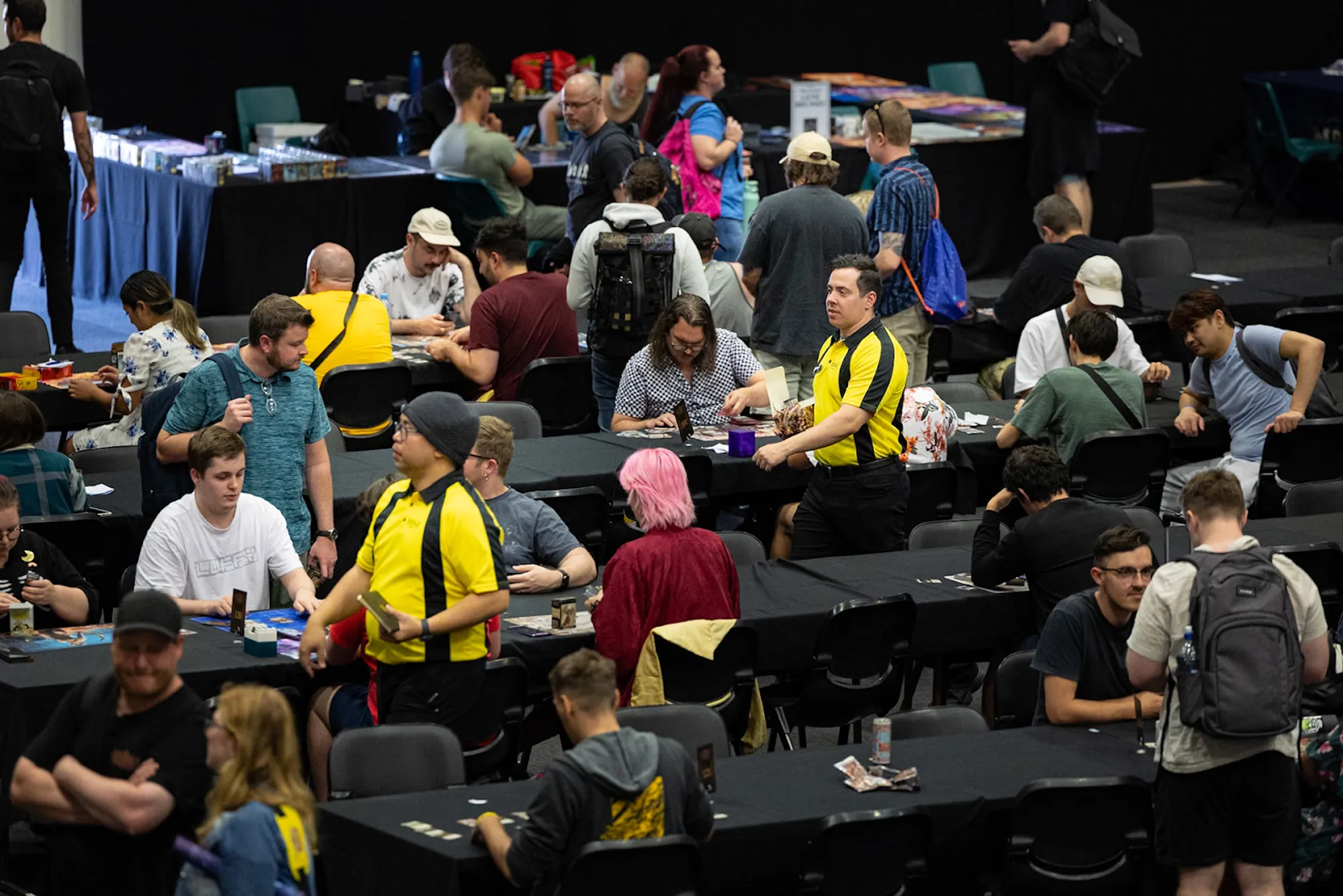 Two FaB judges walking through aisles of players.